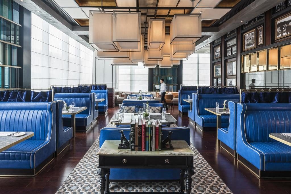 Modern restaurant with bright blue leather banquet seating and square white lighting from the ceiling.