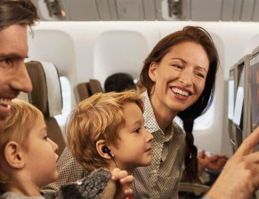 Image of mother and father sitting with their kids on an airplane