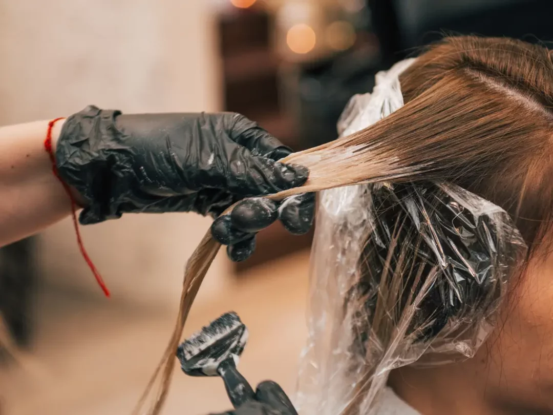 Image of woman getting hair dyed in a salon.