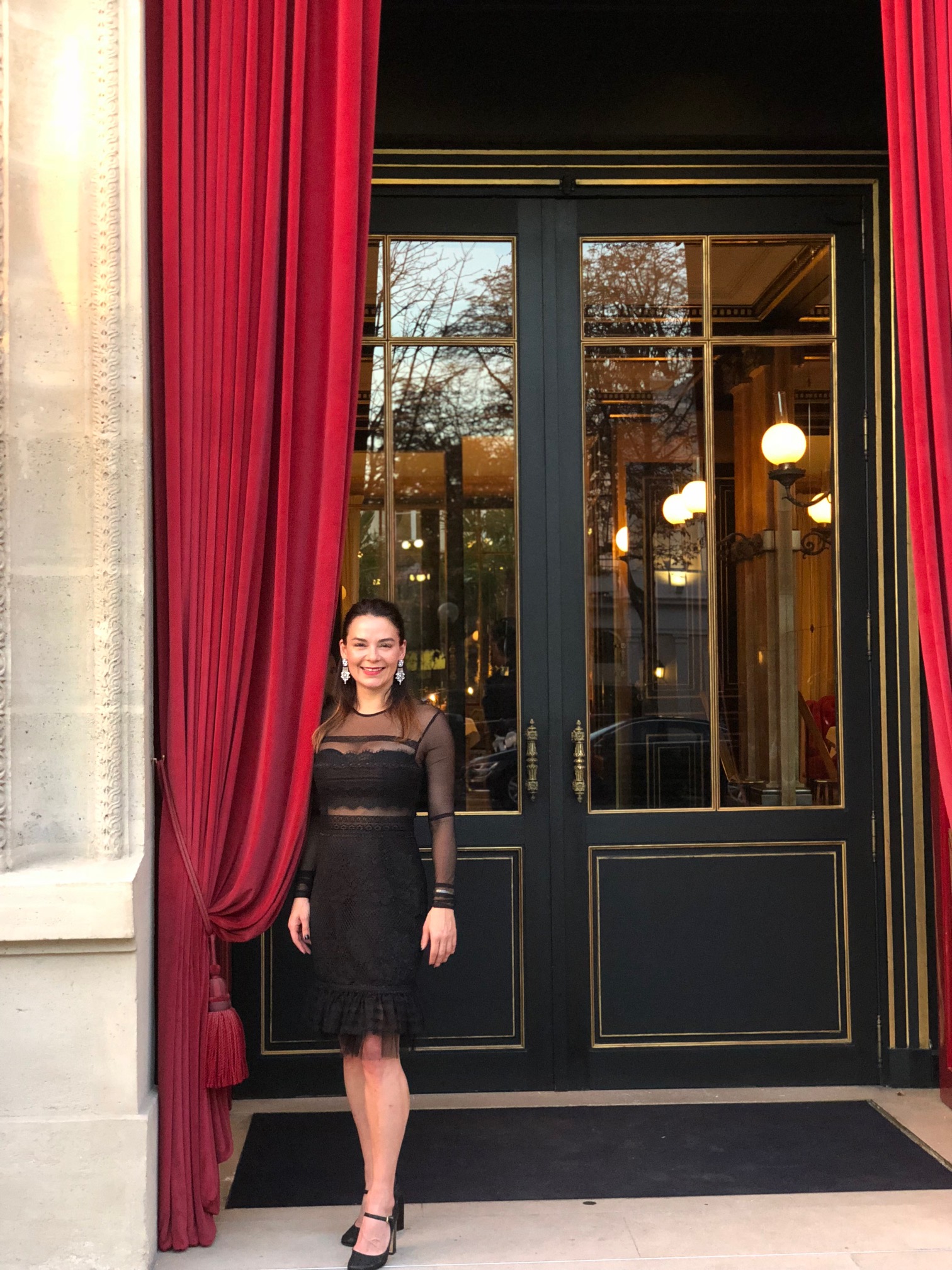 brunette outside lucury hotel in Paris with red curtains