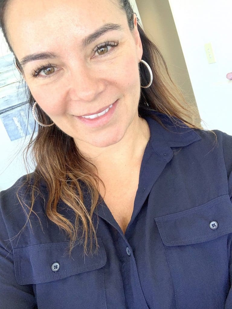 woman in navy shirt looking with clear skin at camera