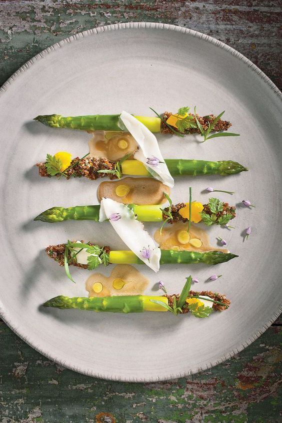 % sticks of asparagus on large white, round playe with ellos sauce and dust on them