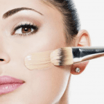 Woman brushing high coverage foundation across her cheek