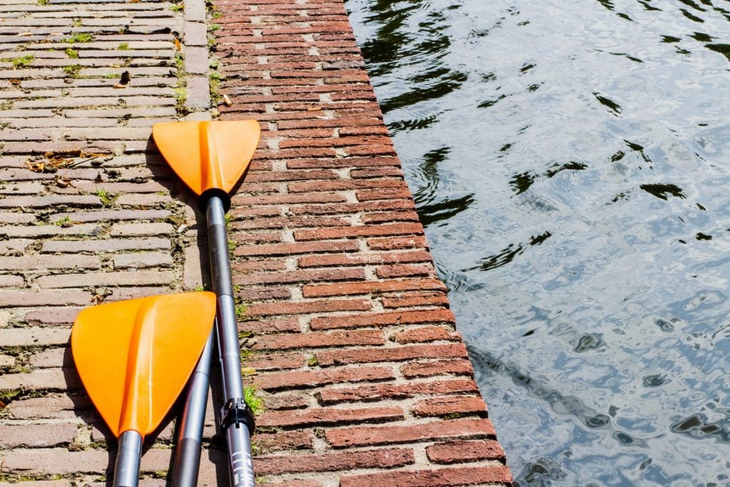 orange paddles on a red brick wall next to the ocean