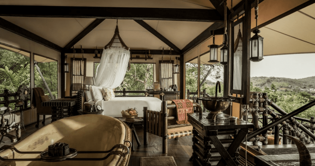 A bedroom with a bathtub in the middle of the living room overlooking the jungle