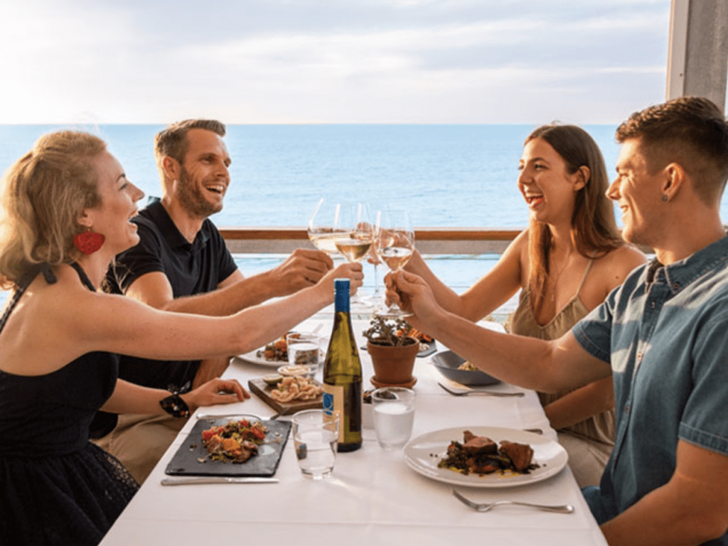 A group of people enjoying a meal near the ocean at Star of Greece in Adelaide