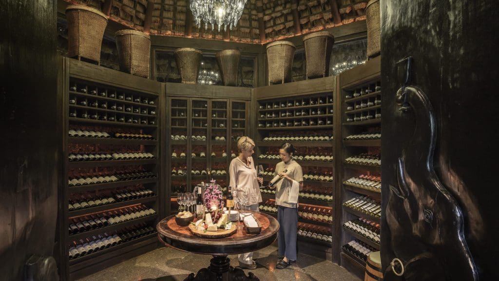 A woman surveying a wine collection while a staff member shows her the wine