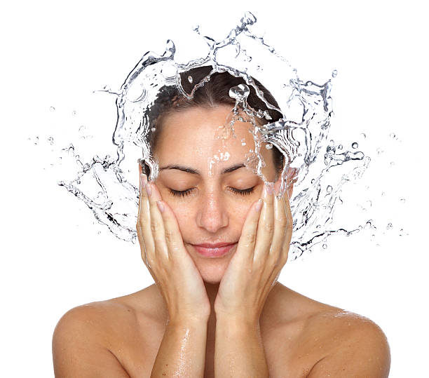 A woman wetting her face with water.