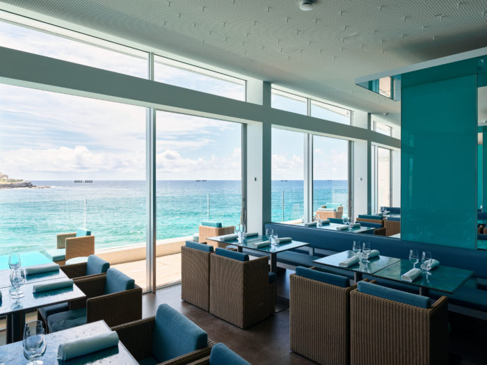 Icerbergs Restaurant and Bar. Blue interior of seats and tables with glass window and ocean oitside. 