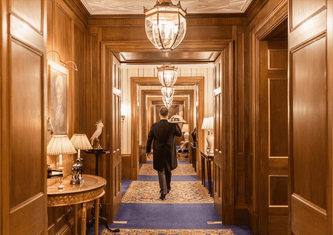 The wooden interior hallway of the London's luxury Lanesborough Hotel, with butler holding tray.